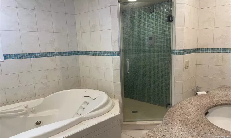 Bathroom featuring tile patterned flooring, shower with separate bathtub, and sink