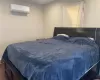 Bedroom featuring dark hardwood / wood-style flooring and an AC wall unit