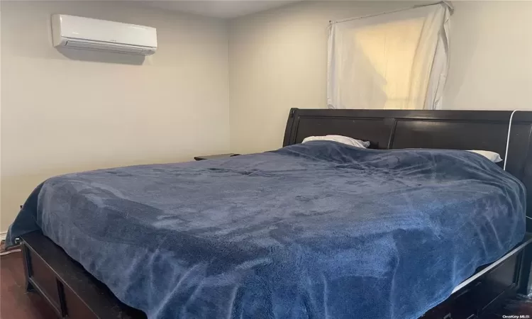 Bedroom featuring dark hardwood / wood-style flooring and an AC wall unit