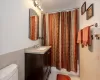 Full bathroom with toilet, tile walls, vanity, shower / bath combo, and tile patterned flooring