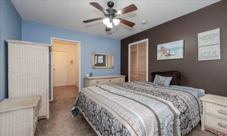 Carpeted bedroom featuring ceiling fan and a closet