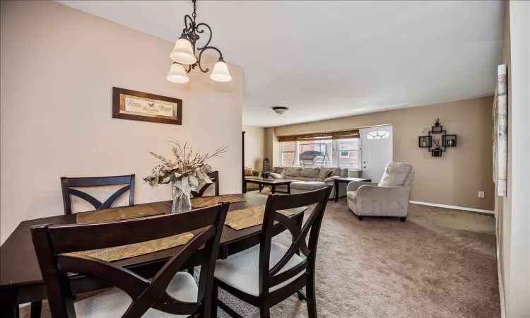 Carpeted dining room featuring a notable chandelier