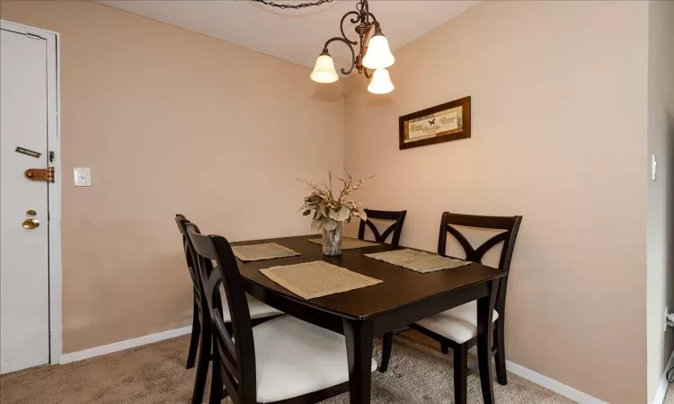 Carpeted dining space with a notable chandelier