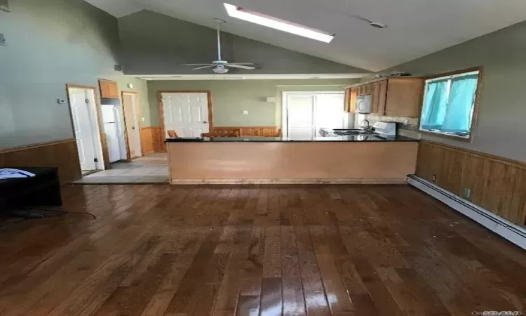 Kitchen featuring baseboard heating, light hardwood / wood-style floors, white appliances, and kitchen peninsula