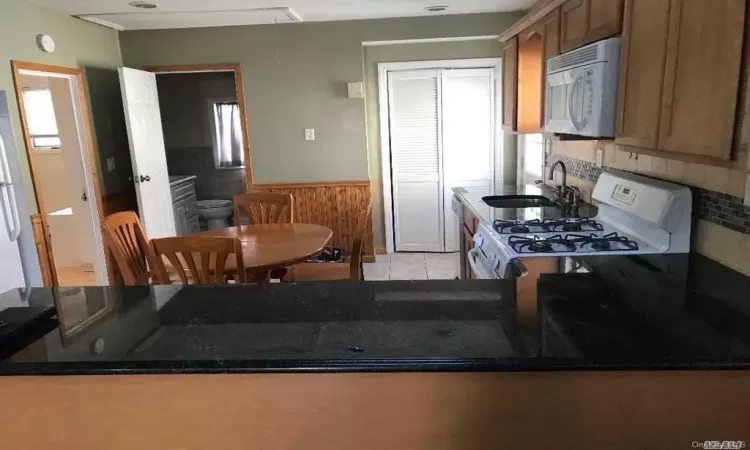 Kitchen featuring sink, white appliances, kitchen peninsula, and light tile patterned flooring