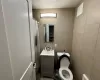 Bathroom featuring vanity, toilet, and tile walls