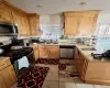 Kitchen featuring light brown cabinets, sink, light tile patterned floors, tasteful backsplash, and stainless steel appliances