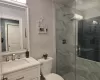 Bathroom with vanity, a shower with door, and toilet