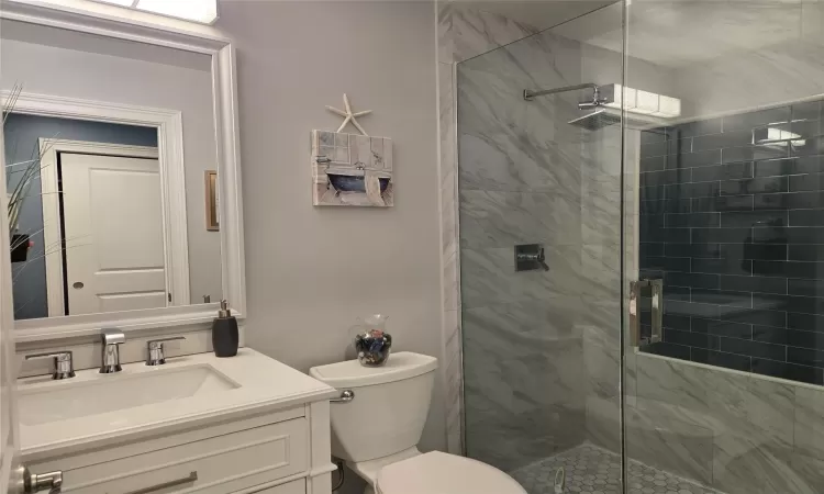 Bathroom with vanity, a shower with door, and toilet