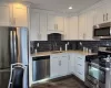 Kitchen featuring sink, dark wood-type flooring, stainless steel appliances, tasteful backsplash, and white cabinets