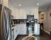 Kitchen featuring dark hardwood / wood-style flooring, tasteful backsplash, stainless steel appliances, and white cabinets