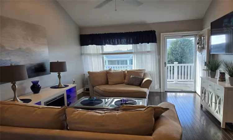 Living room featuring vaulted ceiling, dark hardwood / wood-style floors, and ceiling fan