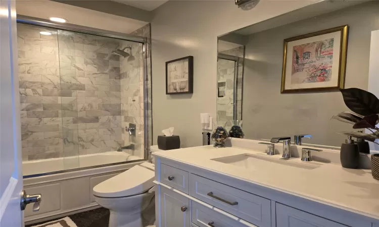 Full bathroom with toilet, vanity, and shower / bath combination with glass door