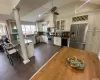 Kitchen with stainless steel appliances, decorative columns, tasteful backsplash, custom range hood, and vaulted ceiling