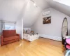 Bedroom featuring an AC wall unit, rail lighting, wood-type flooring, and lofted ceiling