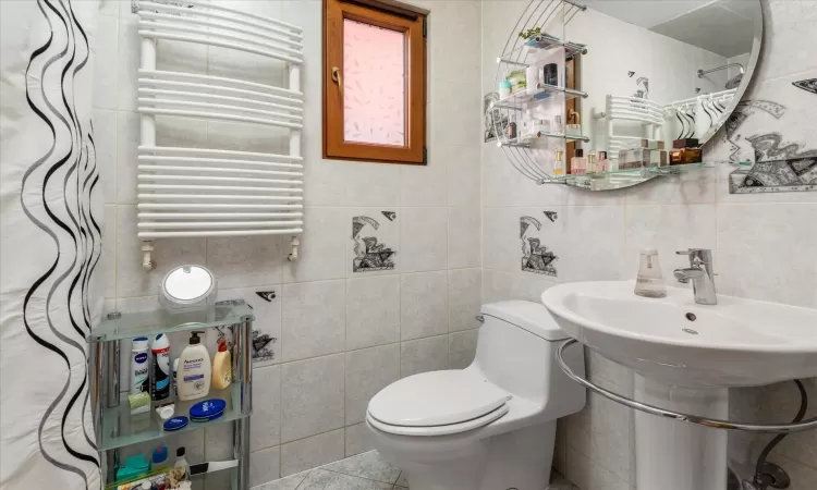 Bathroom featuring radiator, tile walls, and toilet