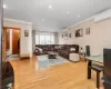 Living room featuring light wood-type flooring, ornamental molding, and an AC wall unit