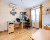 Office area with light hardwood / wood-style floors, an AC wall unit, and a baseboard radiator