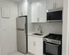 Kitchen featuring sink, appliances with stainless steel finishes, electric panel, decorative backsplash, and white cabinets