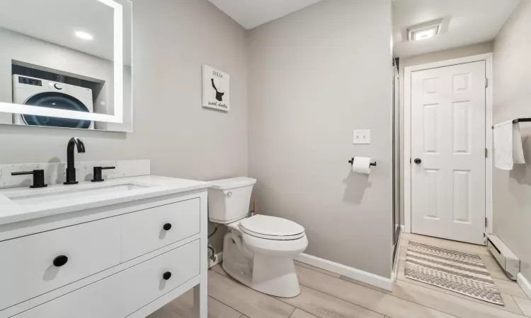 Bathroom with vanity, toilet, and baseboard heating