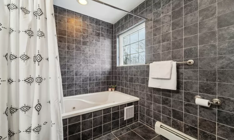 Bathroom featuring tiled shower / bath and a baseboard heating unit