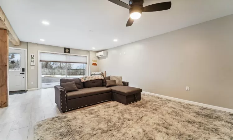 Living room featuring a wall mounted air conditioner and ceiling fan