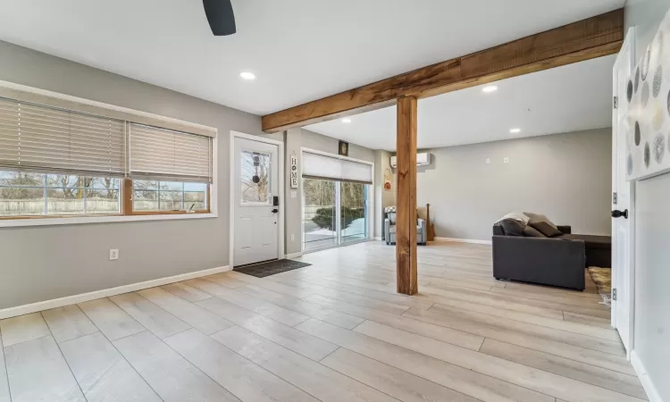 Foyer entrance featuring beamed ceiling, ceiling fan, a wall mounted AC, and light wood-type flooring