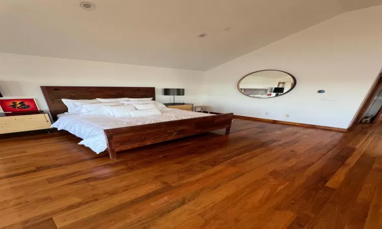 Bedroom with lofted ceiling and hardwood / wood-style floors