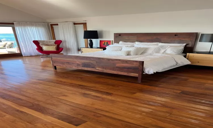 Bedroom featuring hardwood / wood-style flooring, lofted ceiling, and access to outside