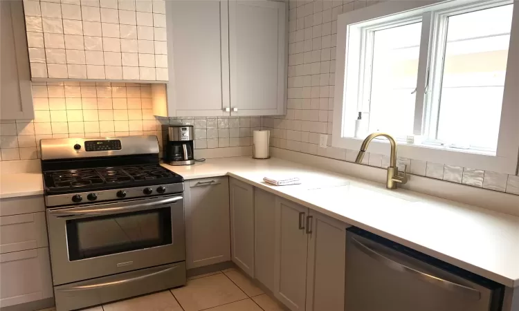 Kitchen with stainless steel appliances, tasteful backsplash, sink, and gray cabinetry