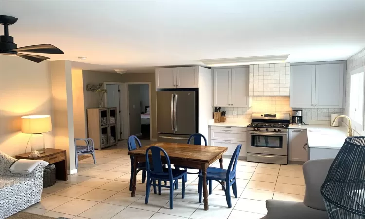 Kitchen with sink, gray cabinets, appliances with stainless steel finishes, backsplash, and light tile patterned flooring