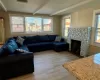 Living room featuring beamed ceiling, a stone fireplace, and light hardwood / wood-style floors