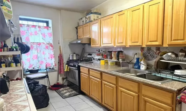 Kitchen with sink, light tile patterned floors, and stainless steel range with gas cooktop