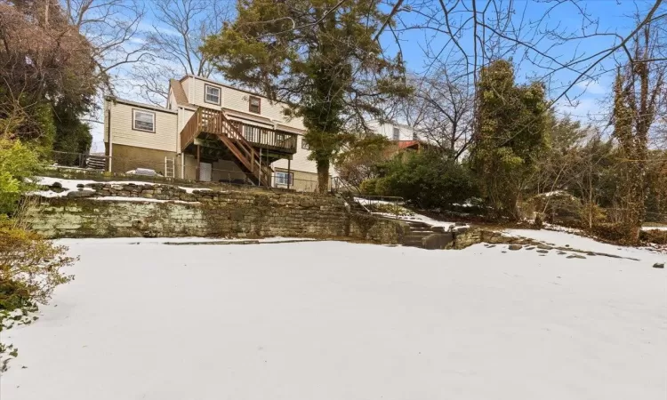 Snow covered house featuring a wooden deck