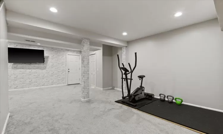 Exercise room featuring carpet flooring and brick wall