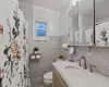 Bathroom featuring vanity, toilet, and tile walls