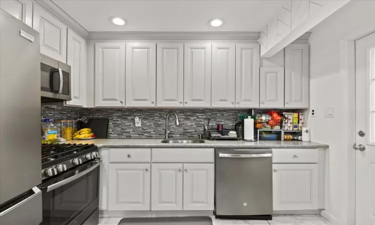 Kitchen featuring white cabinetry, appliances with stainless steel finishes, sink, and backsplash