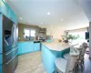 Kitchen featuring wall chimney exhaust hood, appliances with stainless steel finishes, blue cabinets, and a kitchen island