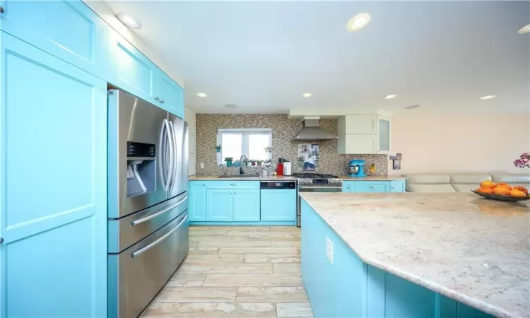 Kitchen with appliances with stainless steel finishes, sink, decorative backsplash, and wall chimney range hood