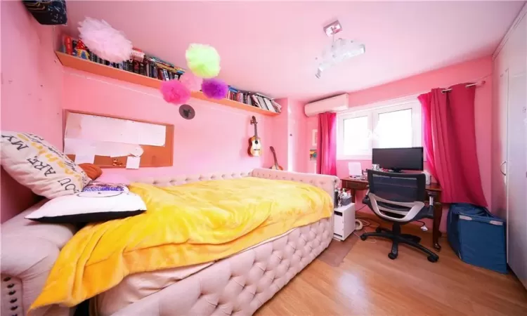 Bedroom featuring a wall mounted air conditioner and light hardwood / wood-style flooring