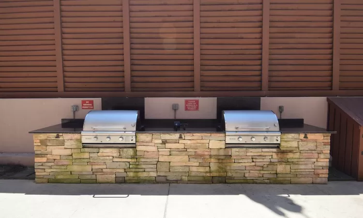 View of patio with an outdoor kitchen and a grill