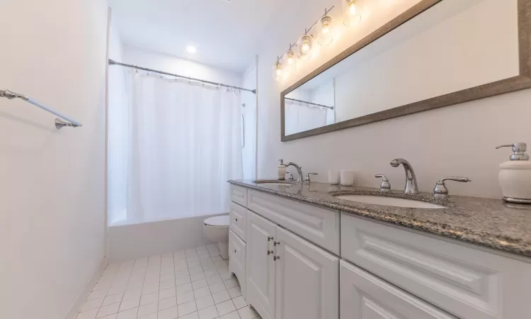 Full bathroom with tile patterned flooring, vanity, shower / bath combination with curtain, and toilet