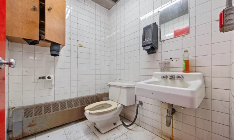 Bathroom featuring tile patterned floors, tile walls, radiator, and toilet