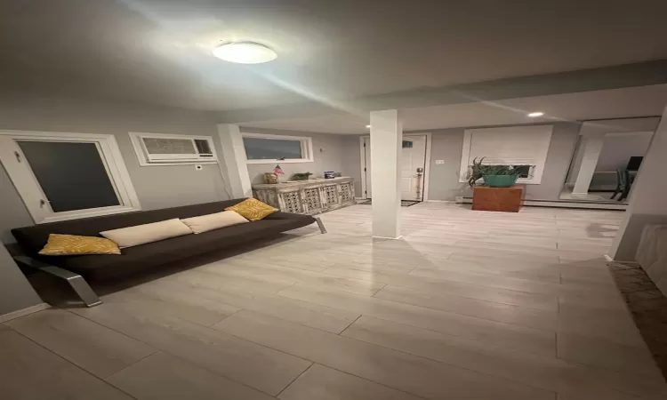 Living room featuring baseboard heating, a wall mounted AC, and light hardwood / wood-style flooring