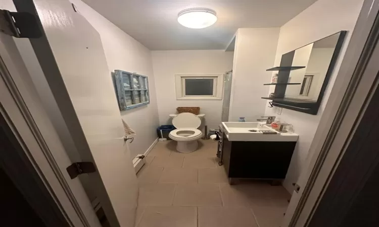 Bathroom with tile patterned floors, toilet, vanity, and a baseboard heating unit