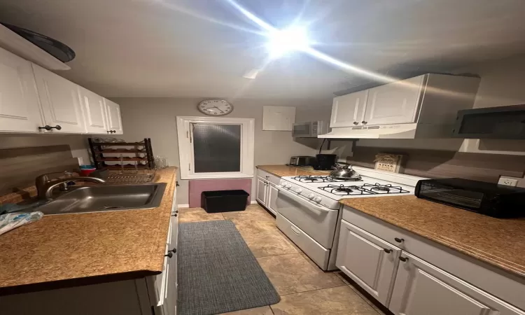 Kitchen with sink, white gas range oven, and white cabinets