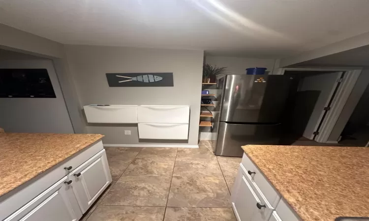 Kitchen with white cabinetry and stainless steel fridge