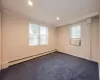 Carpeted spare room featuring a baseboard radiator, plenty of natural light, and crown molding