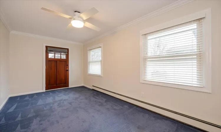 Entryway featuring crown molding, a baseboard radiator, ceiling fan, and dark colored carpet