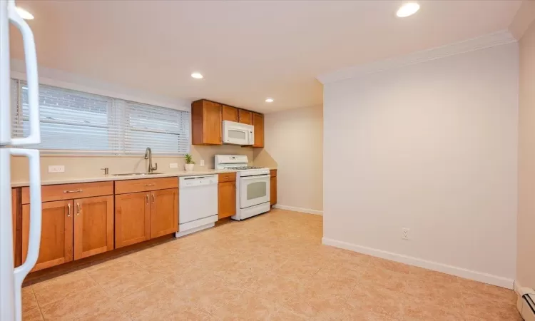 Kitchen with crown molding, white appliances, sink, and a baseboard heating unit